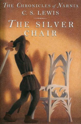 A young boy with a sword above his head about to swing down onto a silver chair