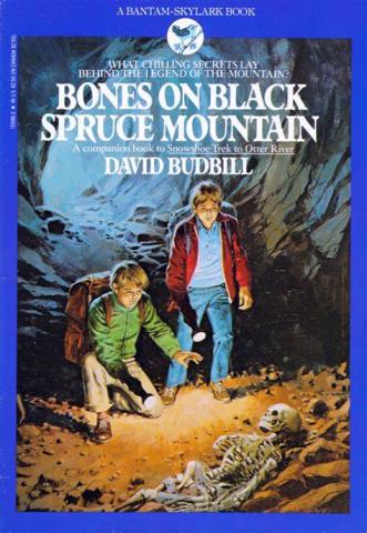 Two young boys in a dark cave looking at a set of human bones with flashlights