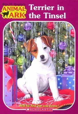 A terrier puppy sitting under a Christmas tree, surrounded by present and has tinsel on its head