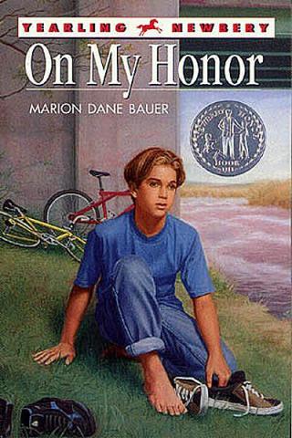 a young boy sitting on a hill next to an overpass with bikes in the background