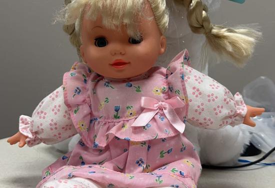 Blonde baby doll with a white long sleeve and pink floral dress