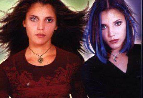 Two twin teenage girls, one with brunette hair wearing red, and the other with dyed blue streaks wearing black