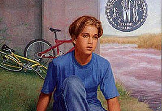 a young boy sitting on a hill next to an overpass with bikes in the background